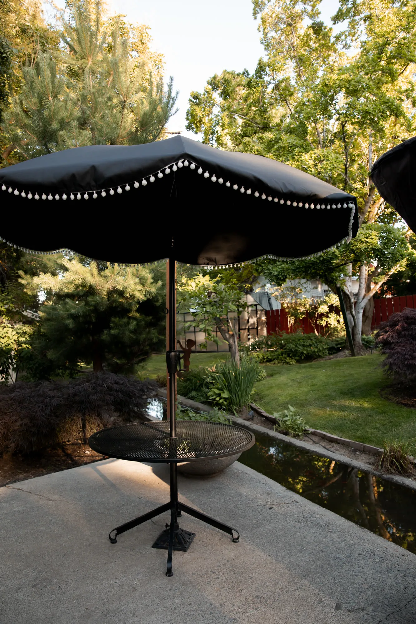 Black patio umbrella with string lights beside the canal