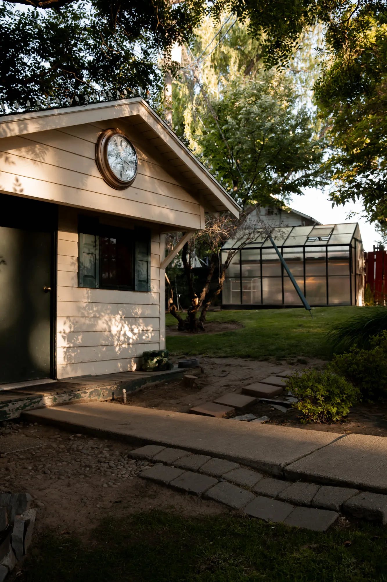 Potting shed with a clock window and the greenhouse beyond